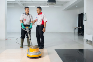 Staff cleaning terlatih berpengalaman sedang membersihkan lantai kantor dengan peralatan profesional, memastikan kebersihan optimal dan standar keselamatan kerja yang tinggi untuk lingkungan bisnis yang sehat dan produktif.